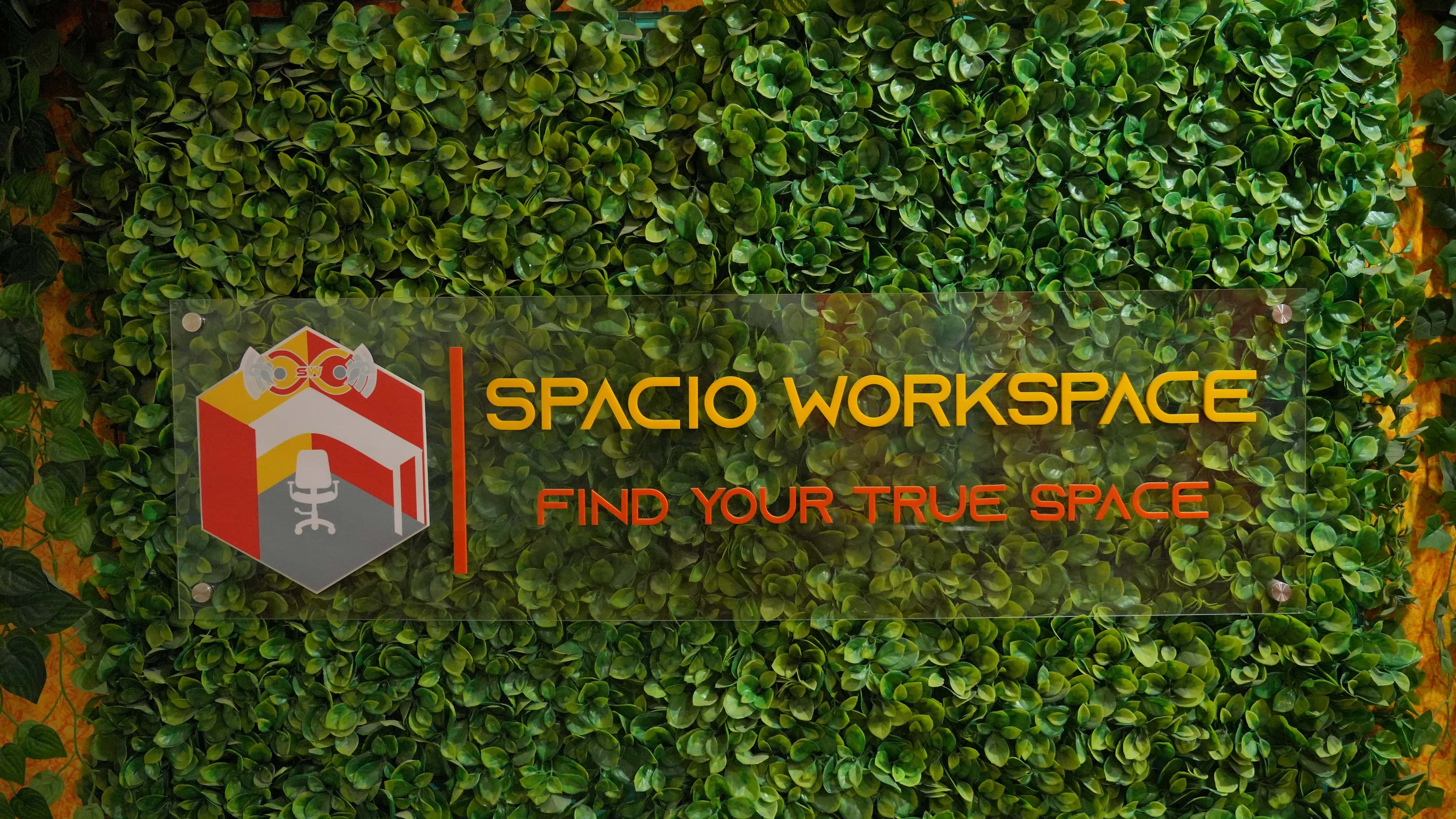 Spacio Workspace sign on green plant wall - Find Your True Space